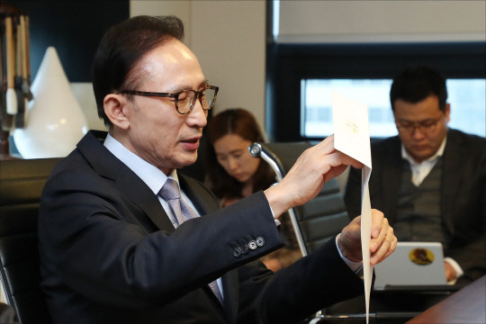 이명박 전 대통령이 1월 31일 오후 서울 강남구 사무실을 찾은 한병도 청와대 정무수석으로부터 전달받은 평창 동계올림픽 초청장을 개봉하고 있다.  연합뉴스